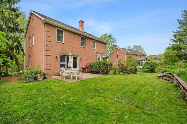 back of property with a chimney, a patio, and brick siding