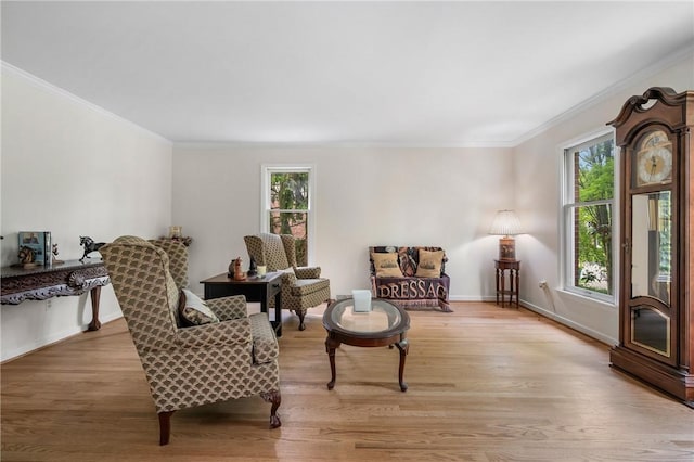 sitting room with healthy amount of natural light, light wood-style flooring, ornamental molding, and baseboards