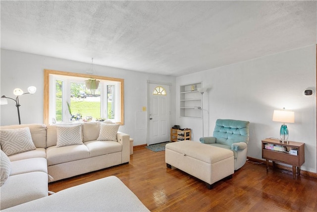 living room with wood finished floors, built in features, a textured ceiling, and baseboards