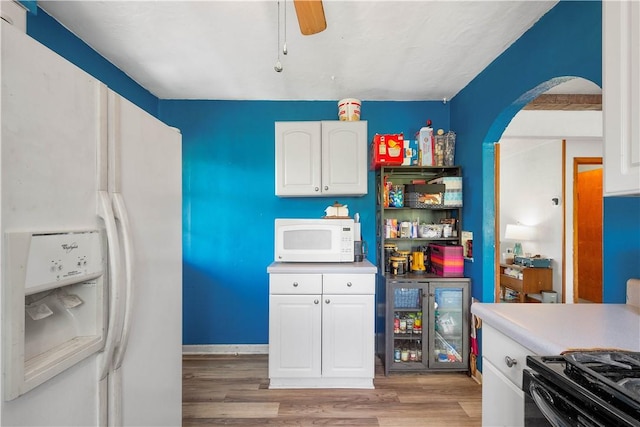 kitchen featuring white appliances, arched walkways, light wood finished floors, white cabinets, and ceiling fan
