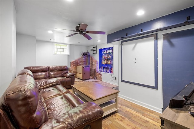 living area with light wood-style floors, a wood stove, recessed lighting, a ceiling fan, and baseboards