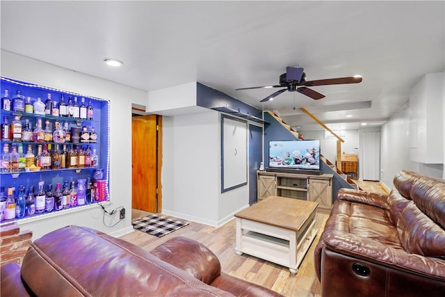 living area with light wood-style flooring, a dry bar, stairs, a ceiling fan, and recessed lighting
