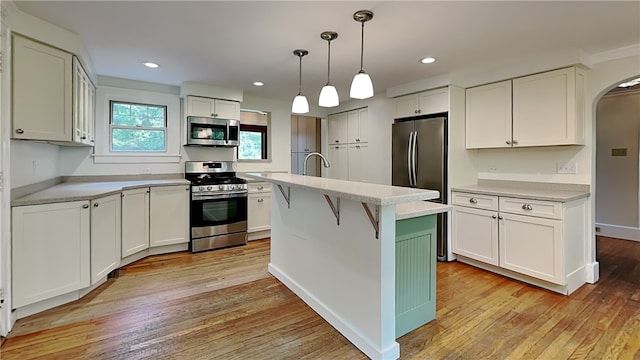 6927 Perrysville Ave, Ben Avon, PA 15202 - kitchen with stainless steel appliances, arched walkways, light countertops, light wood-type flooring, and white cabinets