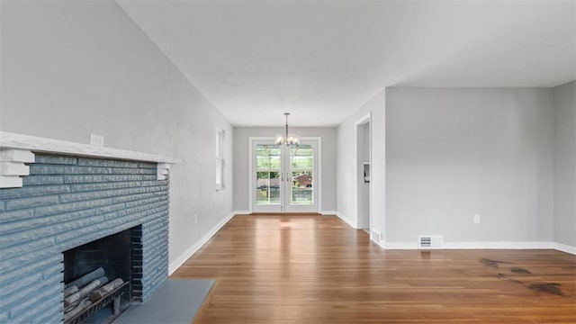 unfurnished living room featuring a chandelier, wood finished floors, baseboards, and a fireplace