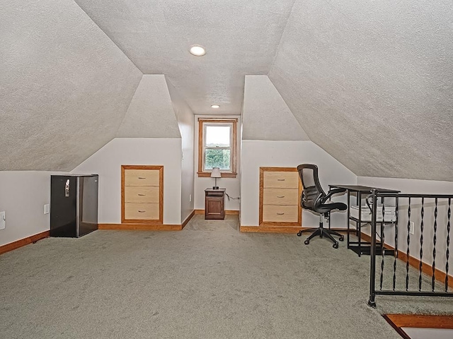 office area featuring a textured ceiling, carpet floors, baseboards, and lofted ceiling