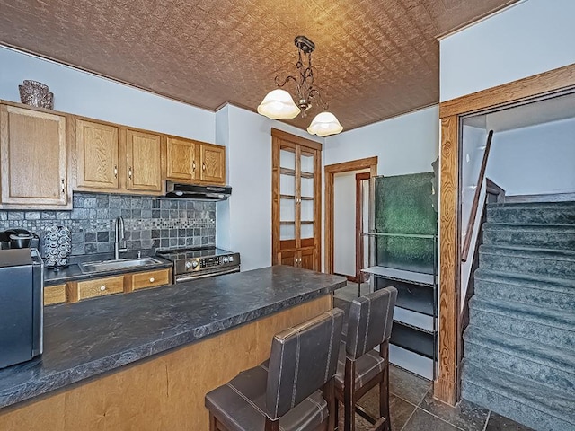 kitchen with stainless steel range with electric stovetop, a sink, tasteful backsplash, under cabinet range hood, and freestanding refrigerator