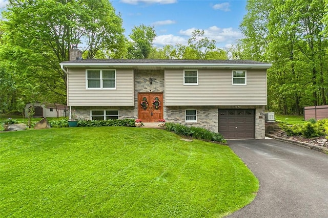 raised ranch featuring driveway, a front lawn, a chimney, and an attached garage