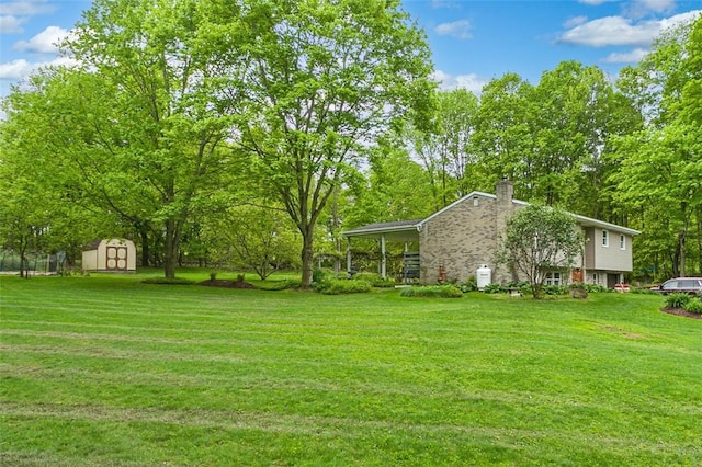 view of grassy yard featuring a shed, an outdoor structure, and a carport