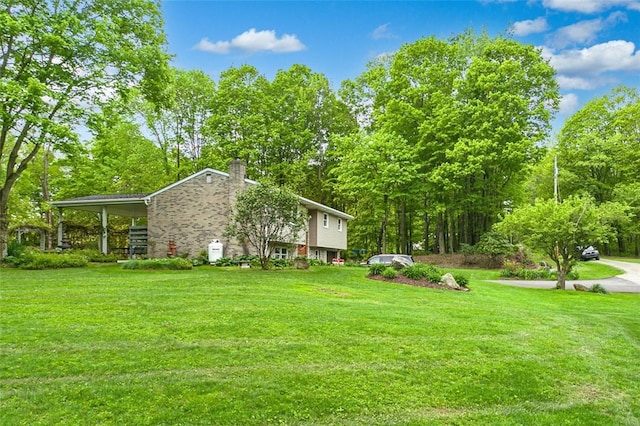 view of green lawn with driveway and a carport