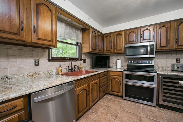 kitchen featuring stainless steel appliances, beverage cooler, a sink, and decorative backsplash