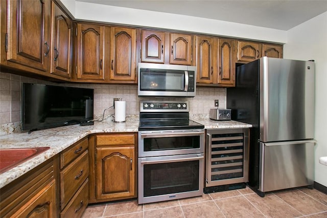 kitchen with stainless steel appliances, beverage cooler, backsplash, light tile patterned floors, and light stone counters