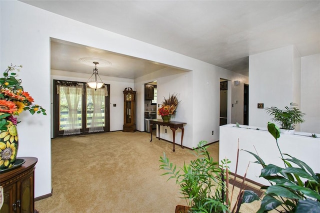 foyer entrance featuring light colored carpet and baseboards