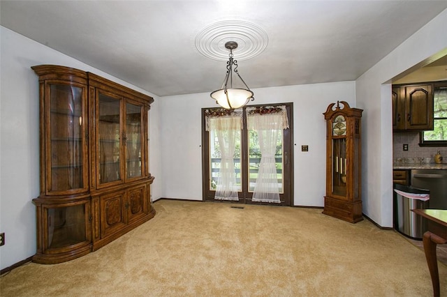 dining space featuring light colored carpet and baseboards