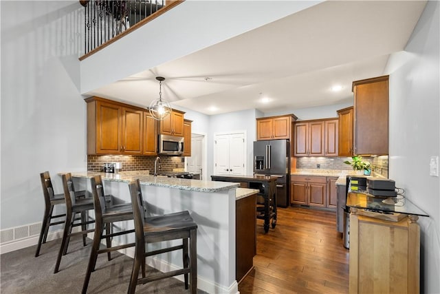 112 Shelton Place Dr, Connoquenessing Boro, PA 16033 - kitchen featuring appliances with stainless steel finishes, a peninsula, backsplash, brown cabinets, and light stone counters