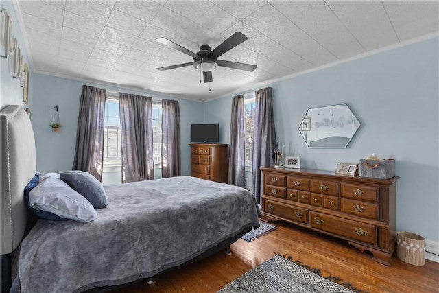 bedroom with wood finished floors, multiple windows, crown molding, and a ceiling fan