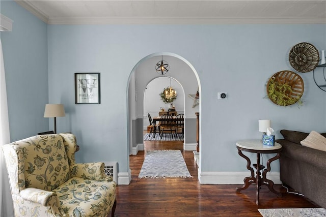 living area featuring arched walkways, wood finished floors, ornamental molding, and baseboards