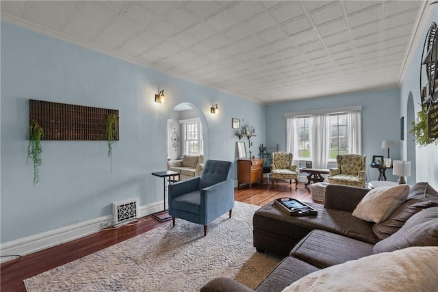 living room featuring arched walkways, crown molding, healthy amount of natural light, wood finished floors, and baseboards