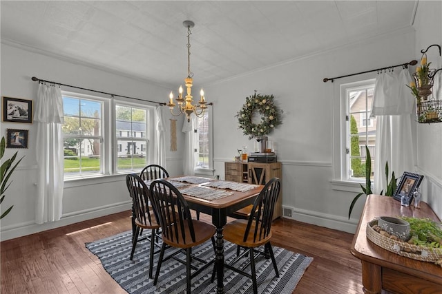 dining space with a chandelier, plenty of natural light, dark wood-style floors, and crown molding