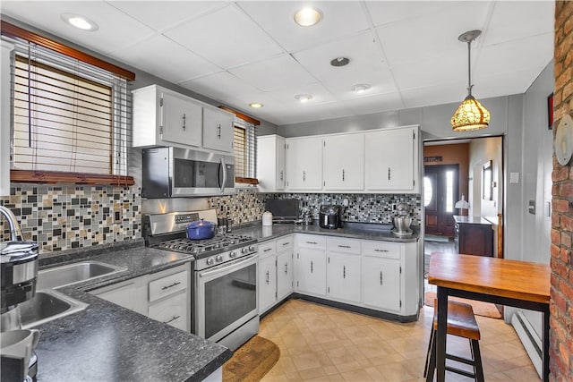 kitchen featuring appliances with stainless steel finishes, dark countertops, tasteful backsplash, white cabinetry, and a paneled ceiling