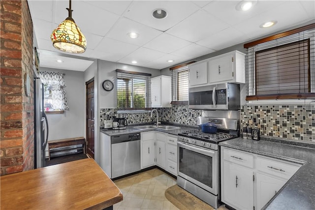 kitchen with stainless steel appliances, a sink, dark countertops, white cabinets, and recessed lighting