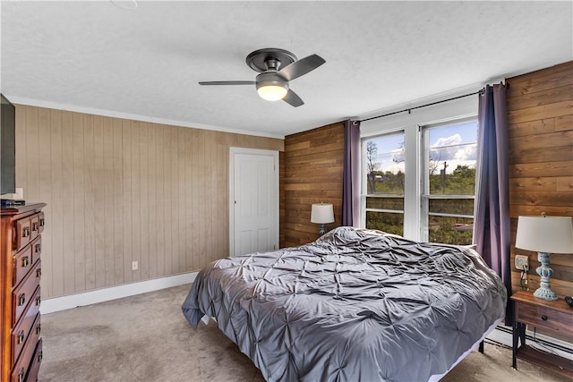 carpeted bedroom featuring wood walls, baseboards, a baseboard radiator, a ceiling fan, and crown molding