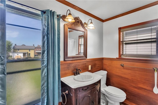 bathroom featuring wainscoting, toilet, ornamental molding, healthy amount of natural light, and vanity
