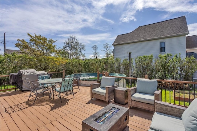 deck featuring an outdoor fire pit, outdoor dining space, and area for grilling