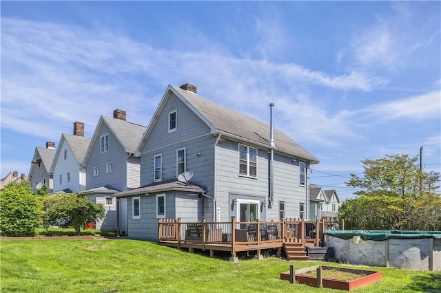 rear view of house featuring a wooden deck, a yard, a covered pool, and a chimney
