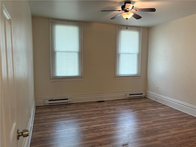 empty room featuring baseboard heating, plenty of natural light, and wood finished floors