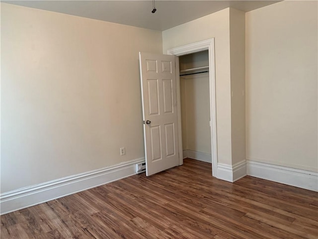 unfurnished bedroom with wood finished floors, baseboards, and a closet