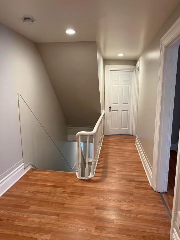 hallway featuring recessed lighting, light wood finished floors, baseboards, and an upstairs landing
