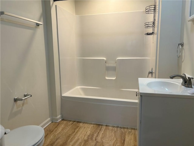 bathroom with wood finished floors, toilet, vanity, bathtub / shower combination, and baseboards