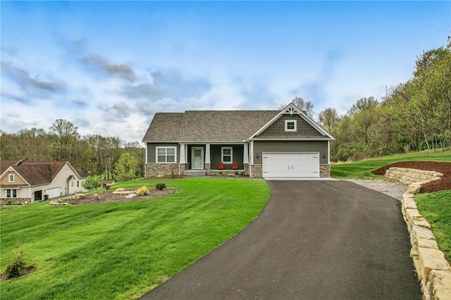 craftsman house with a front yard, driveway, stone siding, and an attached garage