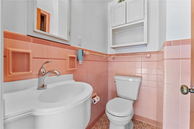 half bathroom with toilet, tile walls, a wainscoted wall, and a sink
