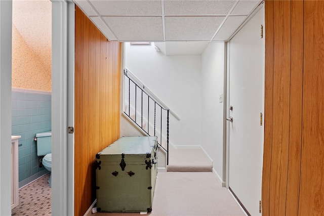 corridor featuring a paneled ceiling and a wainscoted wall