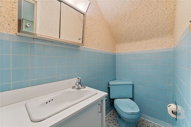 bathroom featuring tile walls, tile patterned floors, toilet, wainscoting, and vanity