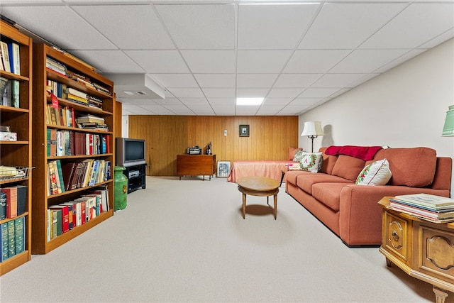 living room featuring wooden walls, carpet, and a paneled ceiling