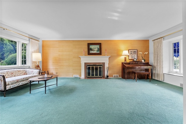 carpeted living room with crown molding, a fireplace with flush hearth, and wooden walls