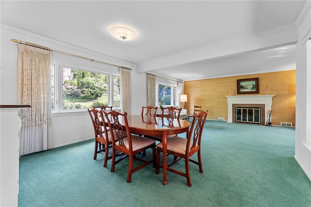 carpeted dining room featuring ornamental molding, a glass covered fireplace, and wood walls