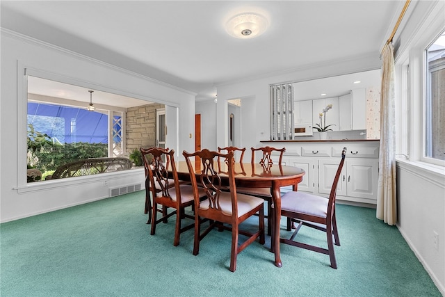 carpeted dining area with ornamental molding, healthy amount of natural light, and baseboards