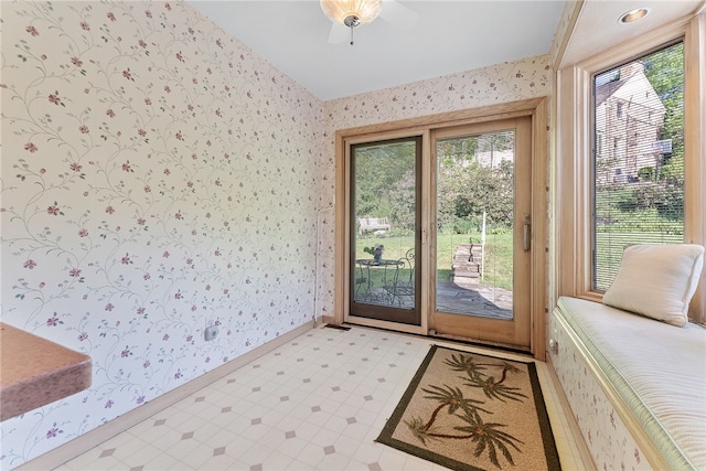 entryway with wallpapered walls, light flooring, lofted ceiling, and baseboards