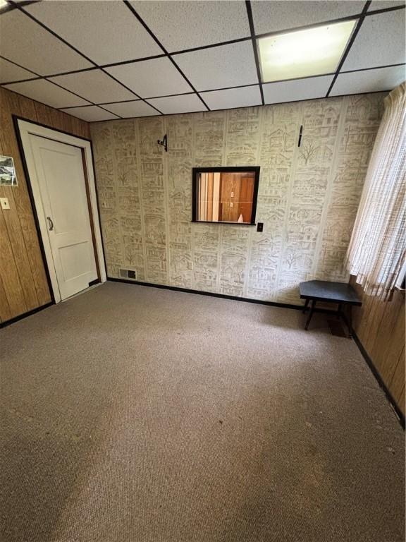 empty room featuring a drop ceiling and carpet floors