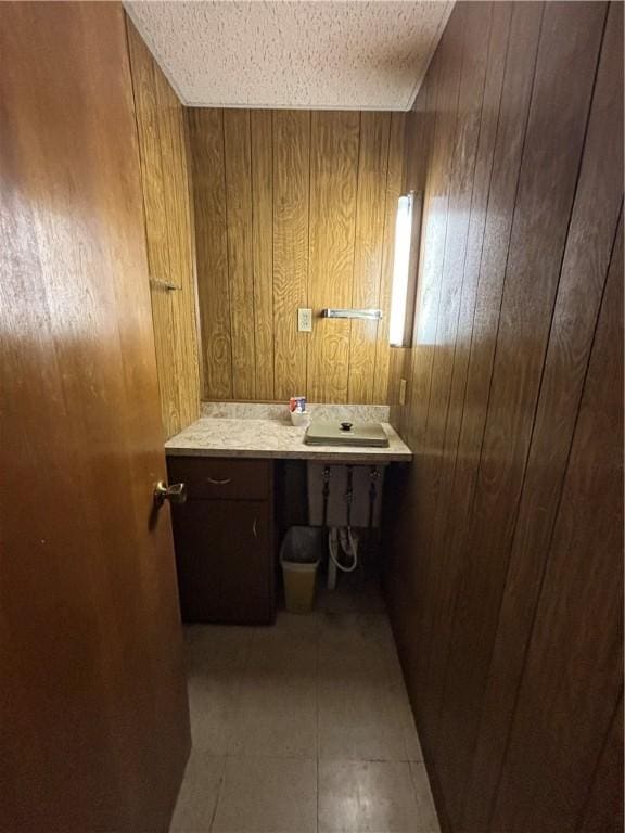 bathroom featuring a sink, wood walls, and a textured ceiling