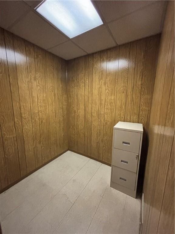 finished basement with a drop ceiling and wood walls