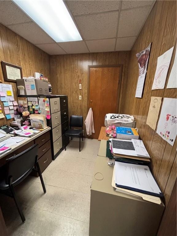 office featuring wooden walls, a drop ceiling, and light flooring