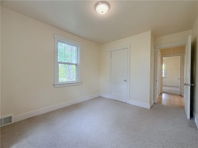 unfurnished bedroom with light colored carpet, baseboards, and a closet