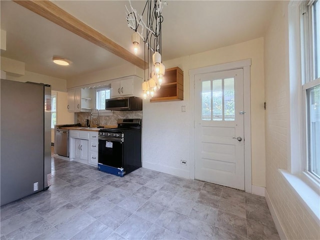 kitchen with appliances with stainless steel finishes, healthy amount of natural light, a sink, and white cabinets