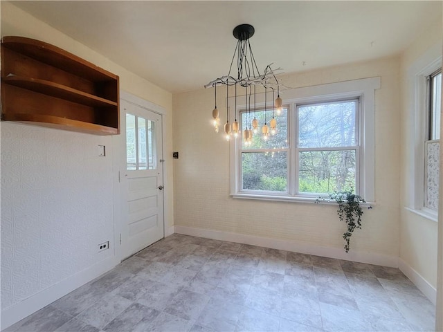 unfurnished dining area with a chandelier, baseboards, and healthy amount of natural light