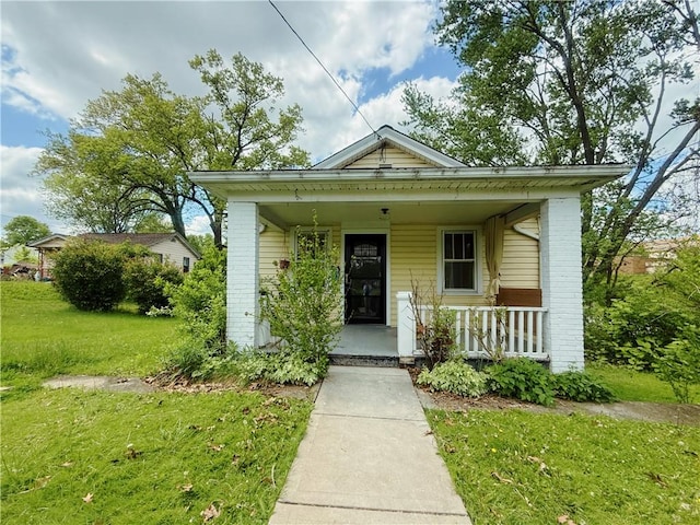 view of front of property featuring brick siding, a porch, and a front lawn
