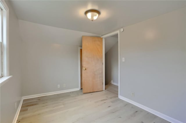 unfurnished bedroom with light wood-style floors, baseboards, and lofted ceiling